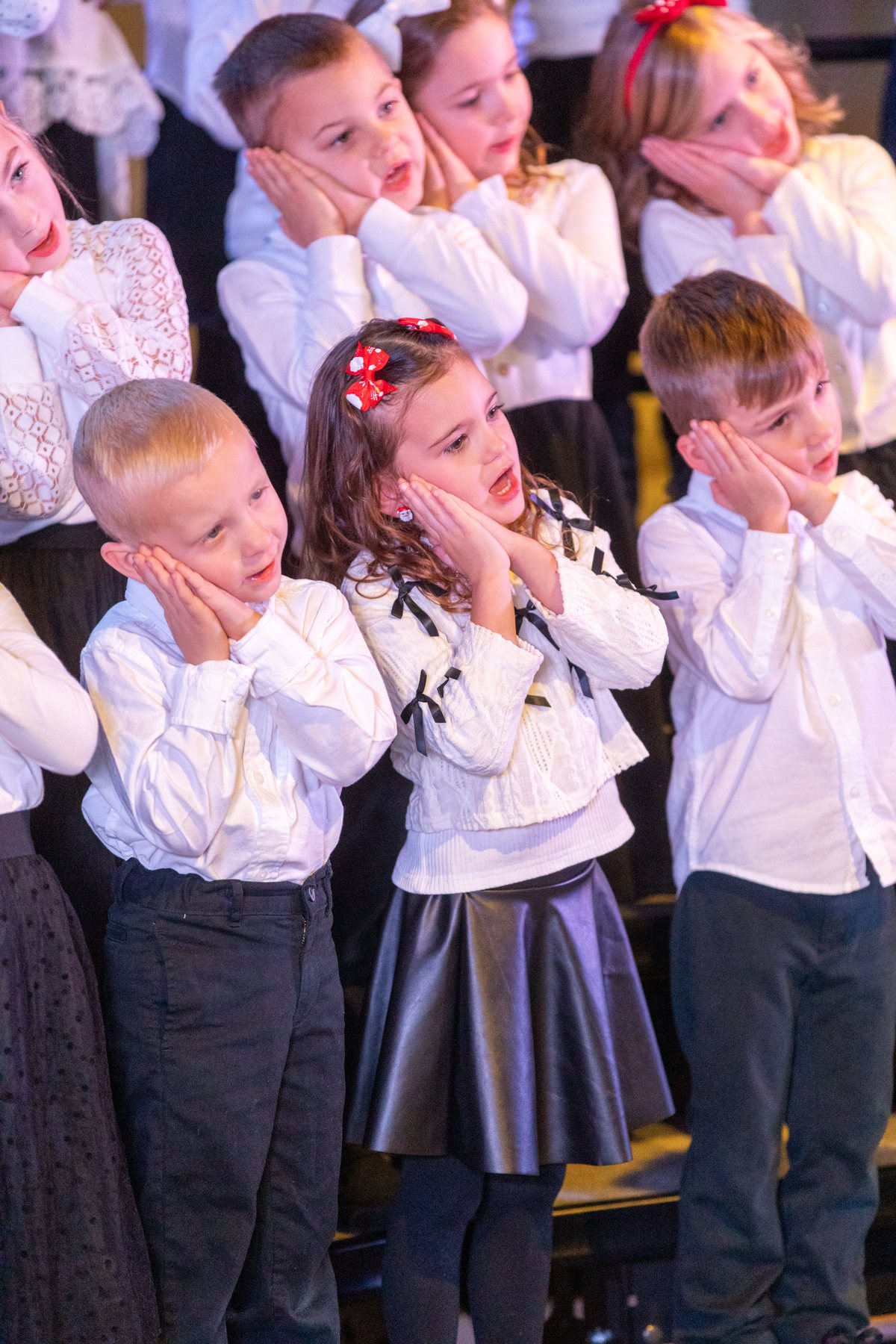Young Troubadours singers with hands on their cheeks during a Christmas concert