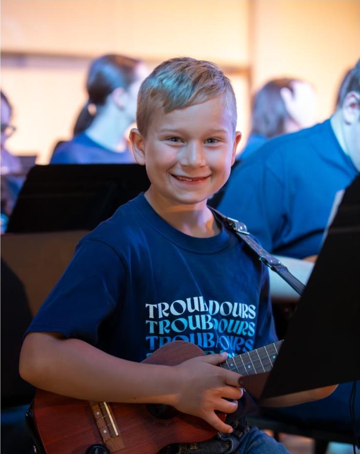 Young student smiling with his ukulele